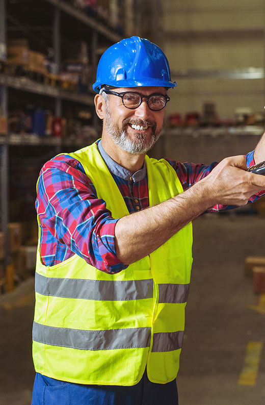 A man inside of a facility wearing a safety vest and smiling at the camera. He represents a BMB Filtration customer.